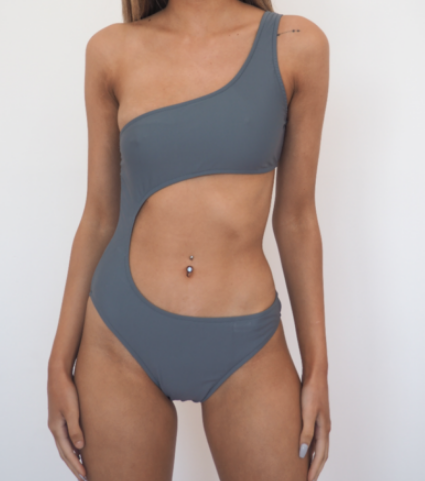 the Kara is a one shoulder one piece with cut away at the torso, high cut leg. Flint grey